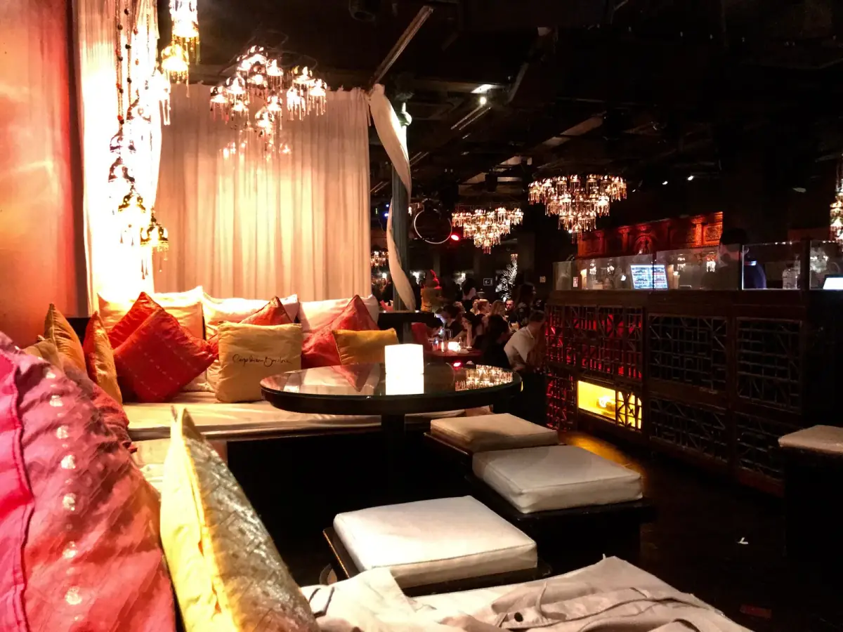 Luxuriöse Lounge-Ecke mit roten Samtkissen, Kristallleuchtern und gedimmtem Licht in elegantem Club mit orientalischem Flair