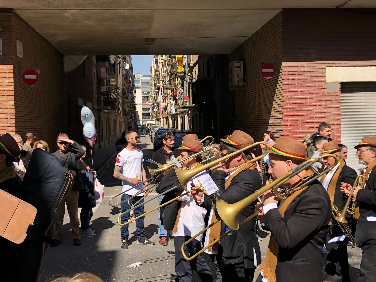 Brass-Band-Musiker in traditioneller Kleidung spielen in einer engen Gasse unter einem Betonvordach