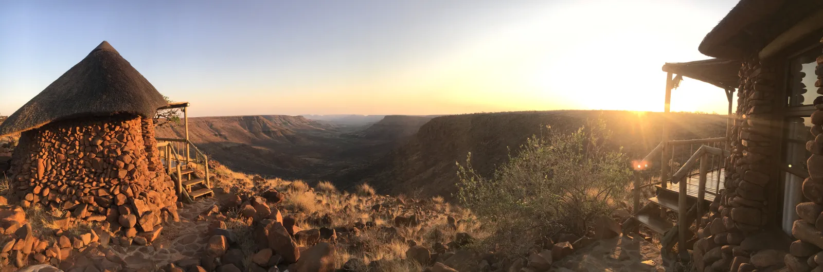 Sonnenaufgang über einer weiten namibischen Landschaft mit rötlichen Felsen