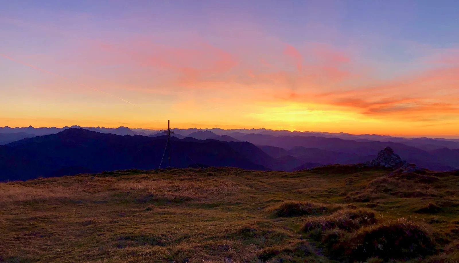 Dramatischer Sonnenuntergang über einer Berglandschaft mit goldenem und orangefarbenem Himmel