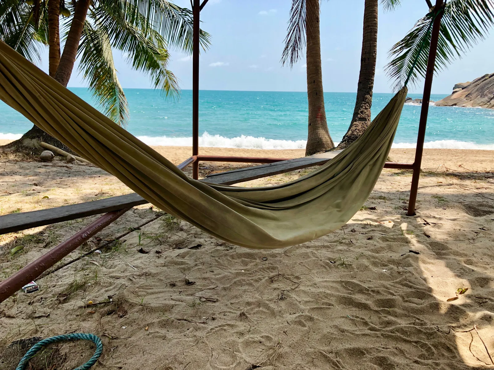 Hängematte zwischen Palmen am Strand mit türkisblauem Meer und Wellen im Hintergrund, Entspannung und Ruhe