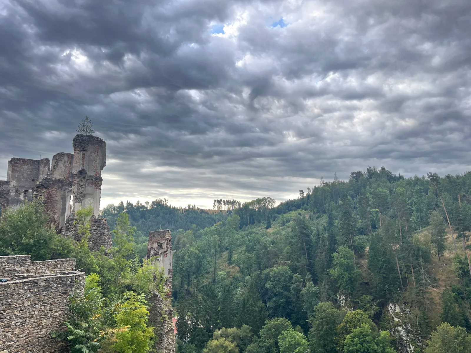 Burgruine mit Granitfelswänden über bewaldetes Waldviertel-Tal unter dramatischem Wolkenhimmel