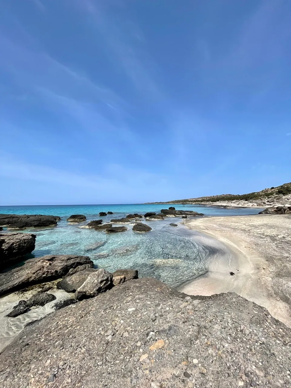 Traumhafte Kieselbucht mit kristallklarem türkisblauem Wasser, Felsbrocken und feinem Sandstrand unter blauem Himmel